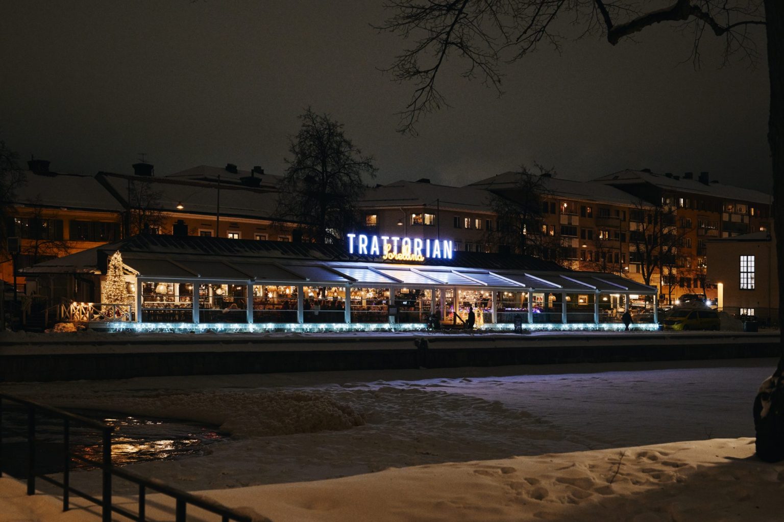 Trattorian Sorellina i Uppsala, en italiensk restaurang, strålar i natten med snö som omger byggnaden.
